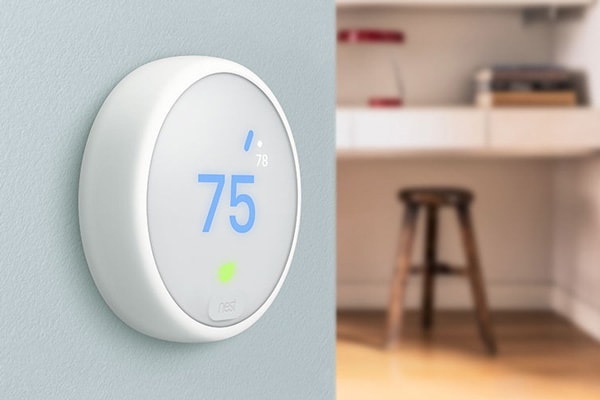 A Nest smart thermostat positioned on a light blue wall