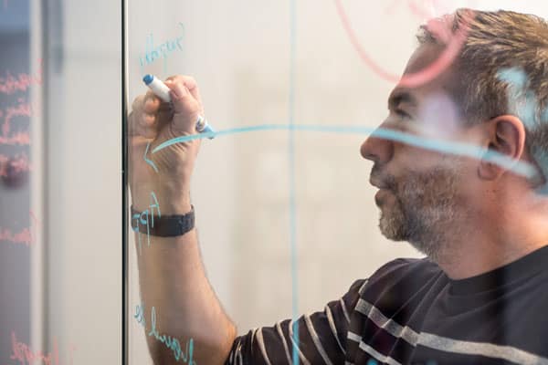 cloud application architecture, middle-aged man writing notes on board