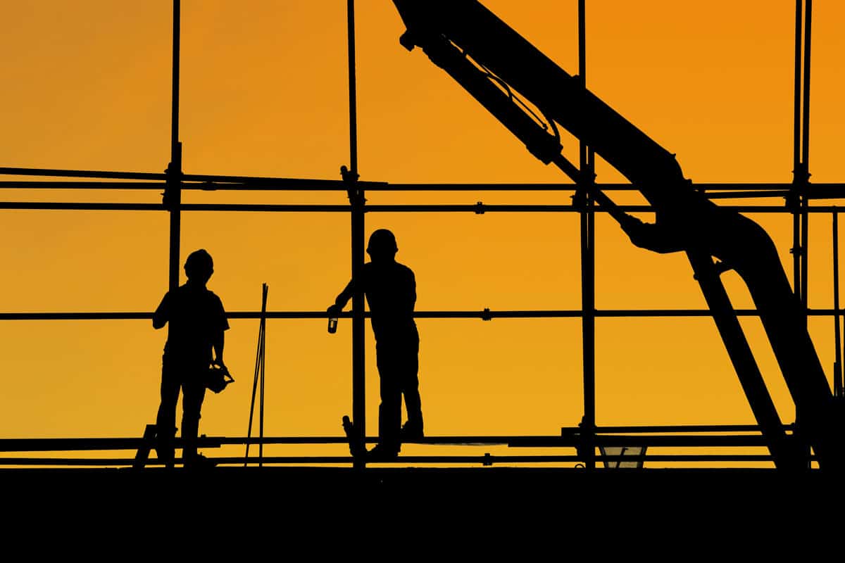 Construction workers standing against a background of the setting sun